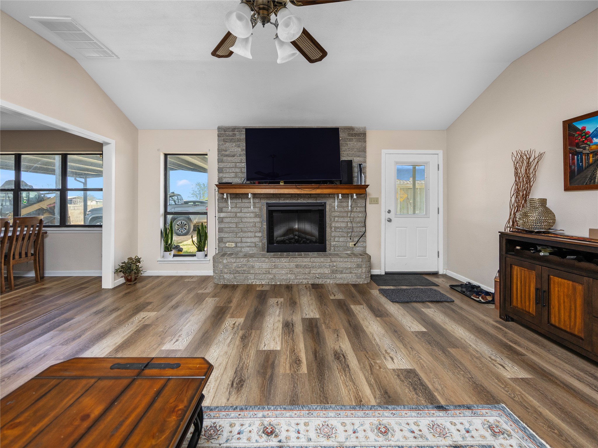 2412 Williamson Road Lockhart, TX 78644 - Photo 5 of 36 Vaulted ceilings enhance this living space featuring wood-finish flooring, a stone-faced fireplace with a wood mantel, and an exterior door with a glass insert