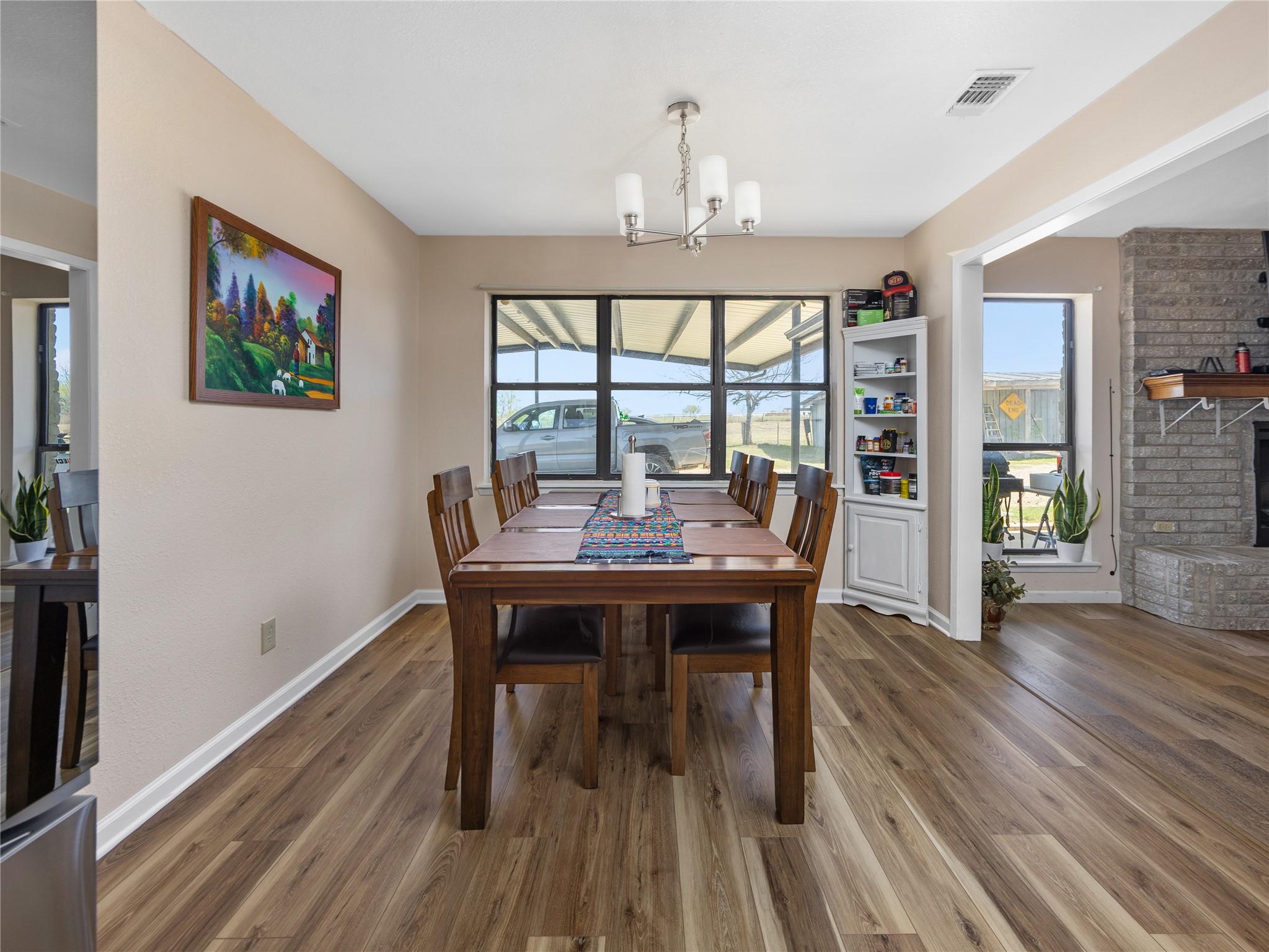 2412 Williamson Road Lockhart, TX 78644 - Photo 7 of 36 Dining area featuring wood-finish flooring, a contemporary chandelier, a built-in corner cabinet, and a large window