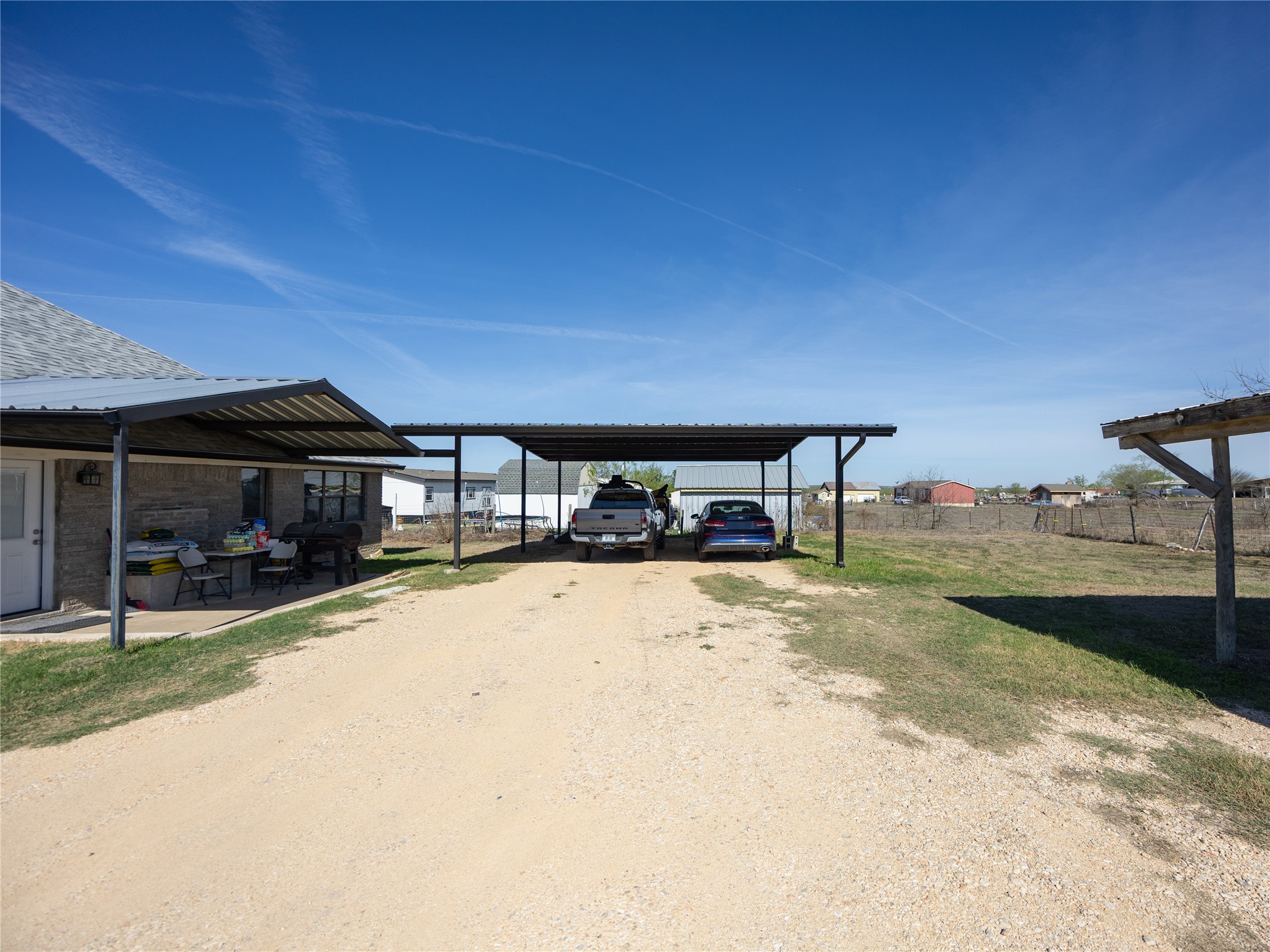 2412 Williamson Road Lockhart, TX 78644 - Photo 9 of 36 Expansive gravel driveway leading to a multi-vehicle carport, offering covered parking