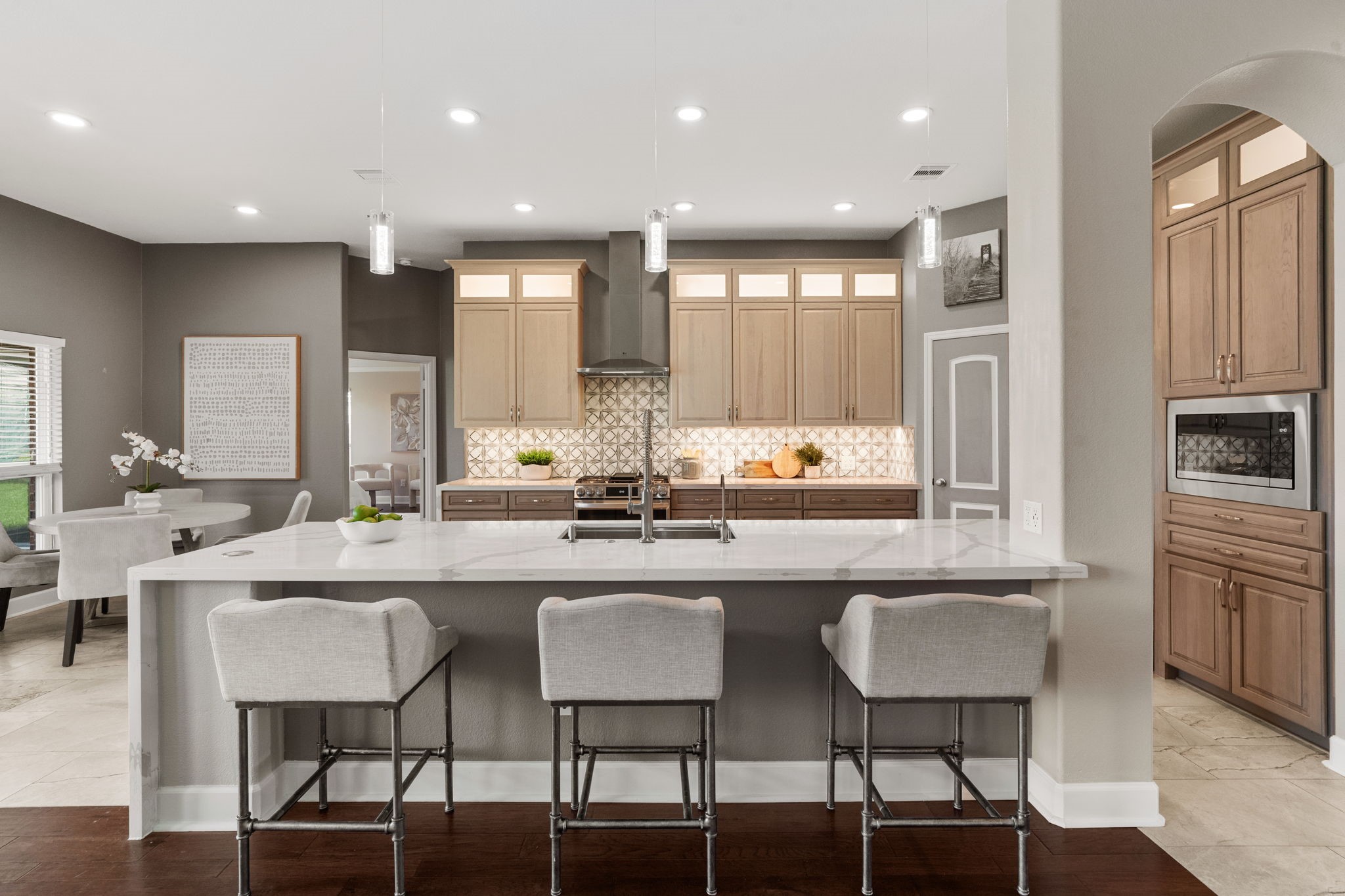 3426 Summer Ranch Drive Katy, TX 77494 - Photo 13 of 48 The kitchen makes a striking impression with a dramatic waterfall quartz island, bar seating, and designer lighting, creating the perfect space for gathering, entertaining, and everyday living.