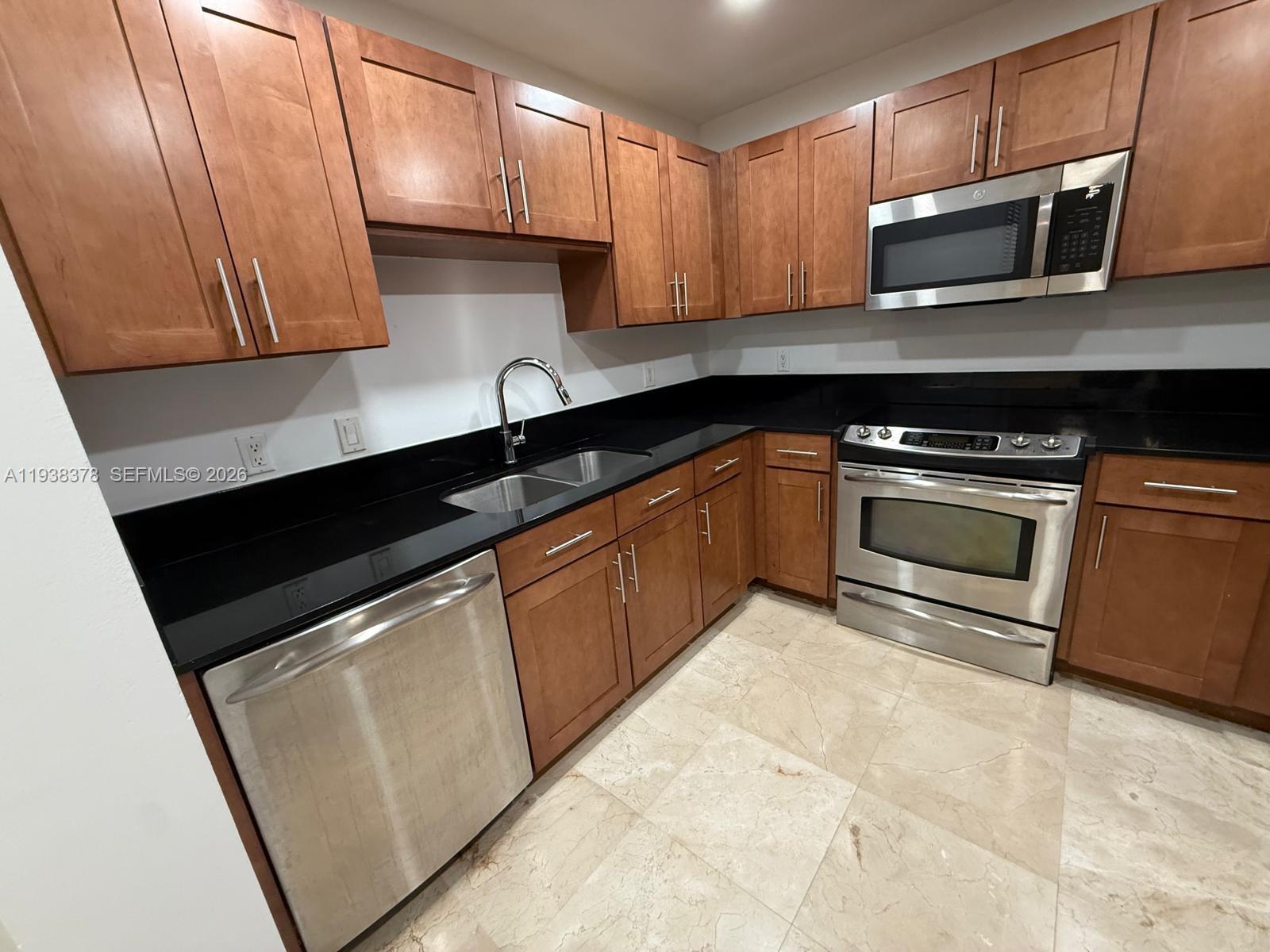 8390 Southwest 72nd Avenue, Unit 520 Miami, FL 33143 - Photo 27 of 61 a kitchen with granite countertop wooden cabinets and a stove top oven