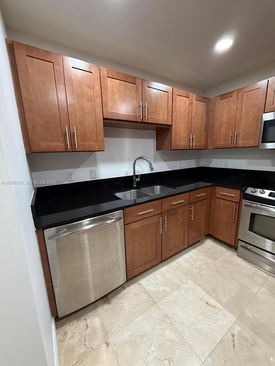 8390 Southwest 72nd Avenue, Unit 520 Miami, FL 33143 - Photo 31 of 61 a kitchen with granite countertop a sink a stove and cabinets