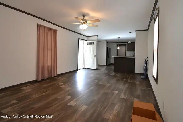 a view of a hallway with wooden floor and a kitchen
