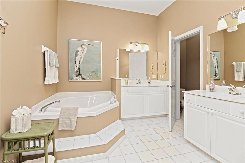 970 Egrets Run, Unit 201 Naples, FL 34108 - Photo 17 of 50 a spacious bathroom with a sink a mirror and a bathtub