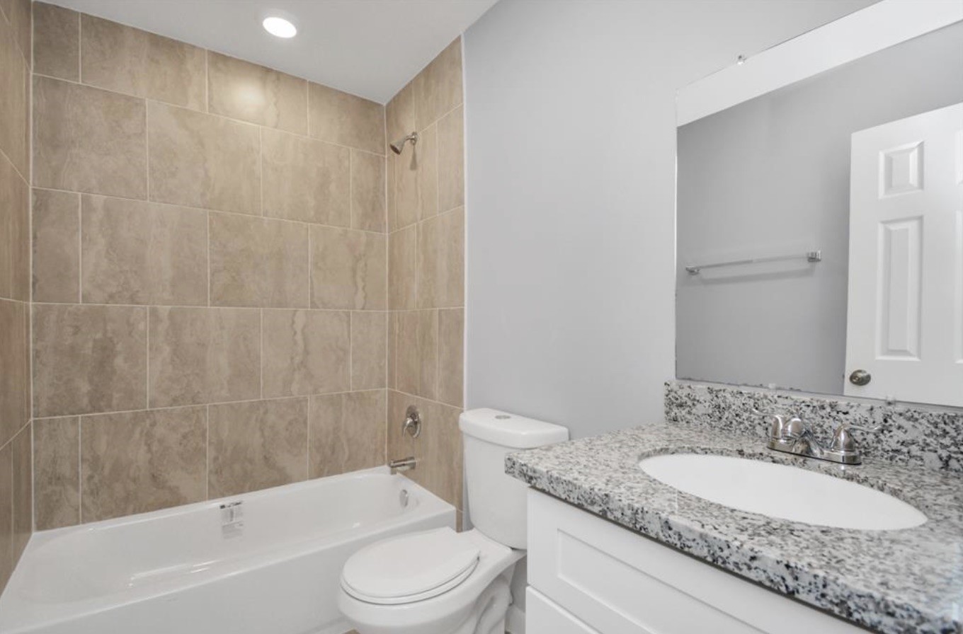 5709 Breland Street, Unit A Houston, TX 77016 - Photo 19 of 26 a bathroom with a granite countertop sink toilet and shower