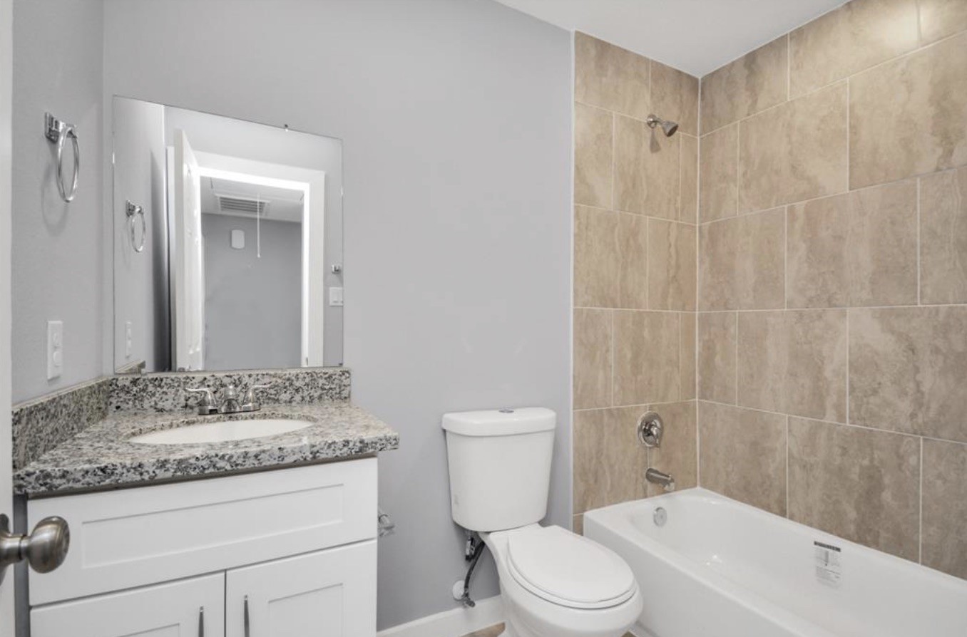5709 Breland Street, Unit A Houston, TX 77016 - Photo 21 of 26 a bathroom with a granite countertop sink a toilet and shower