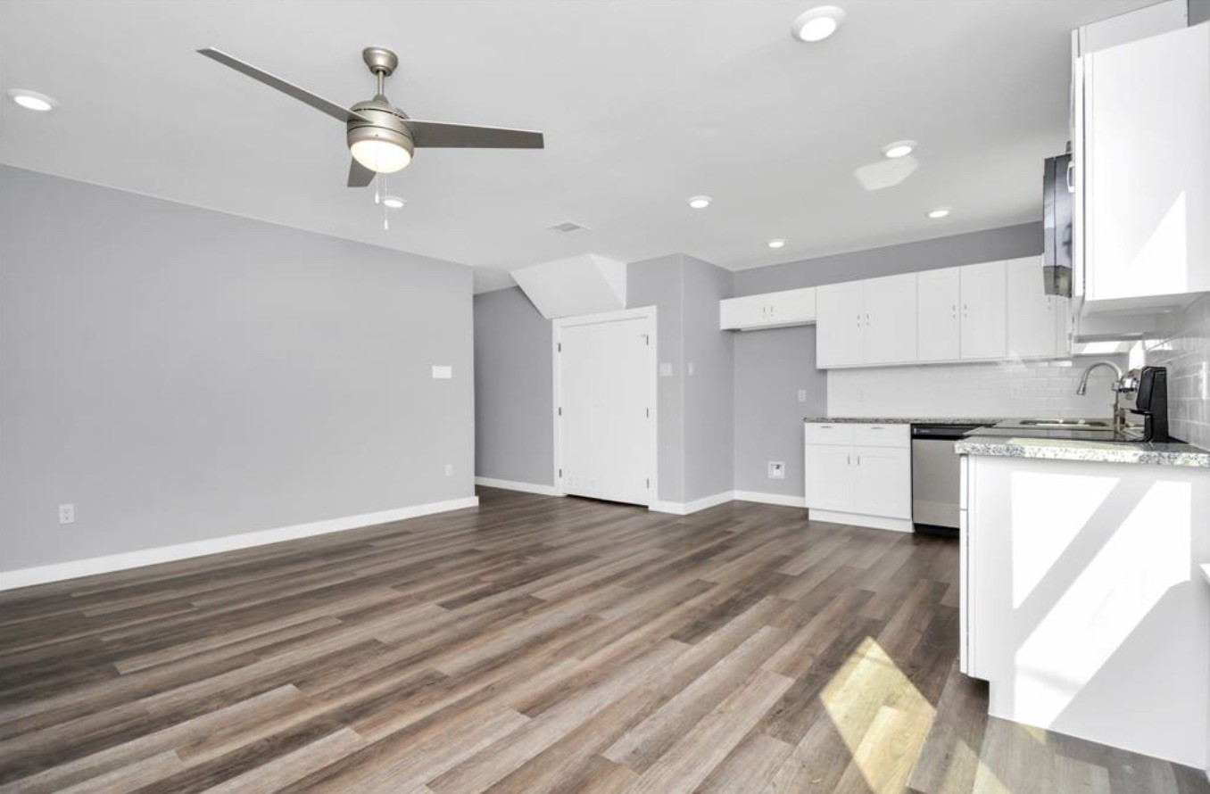 5709 Breland Street, Unit A Houston, TX 77016 - Photo 5 of 26 an empty room with wooden floor a ceiling fan and kitchen view