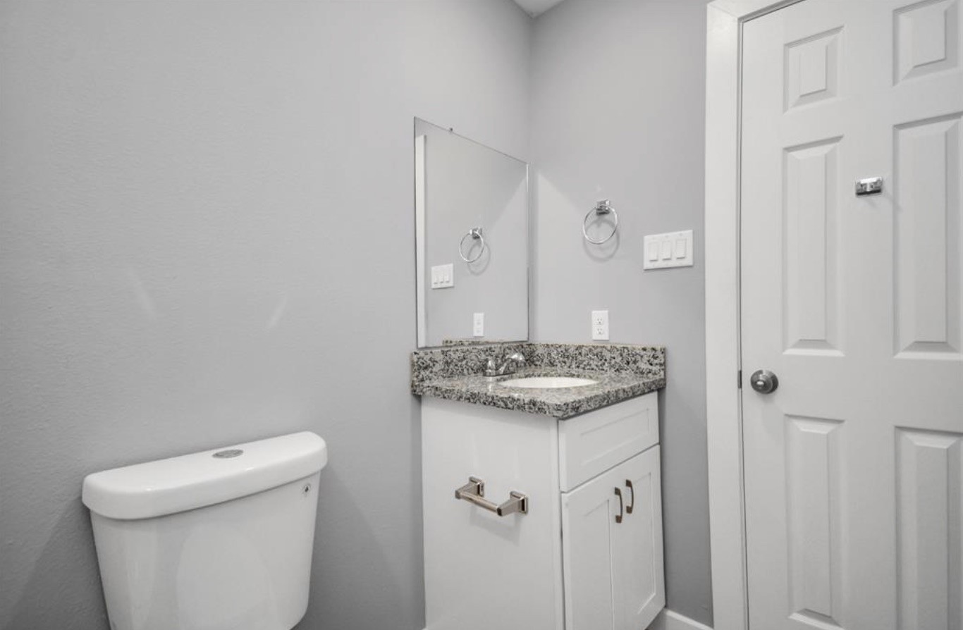 5709 Breland Street, Unit A Houston, TX 77016 - Photo 10 of 26 a bathroom with a granite countertop sink a toilet and a mirror