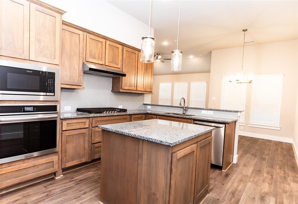 6124 Shasta Creek Road Celina, TX 75009 - Photo 14 of 27 a kitchen with stainless steel appliances granite countertop a sink a stove and a wooden floors