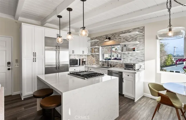 a kitchen with stainless steel appliances kitchen island a table and chairs in it