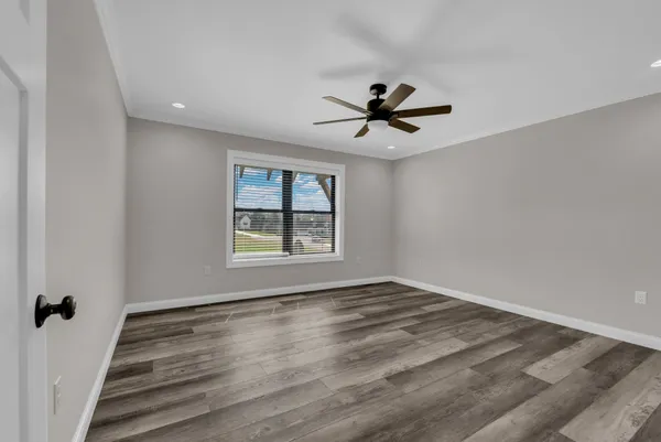 a view of empty room with wooden floor and fan