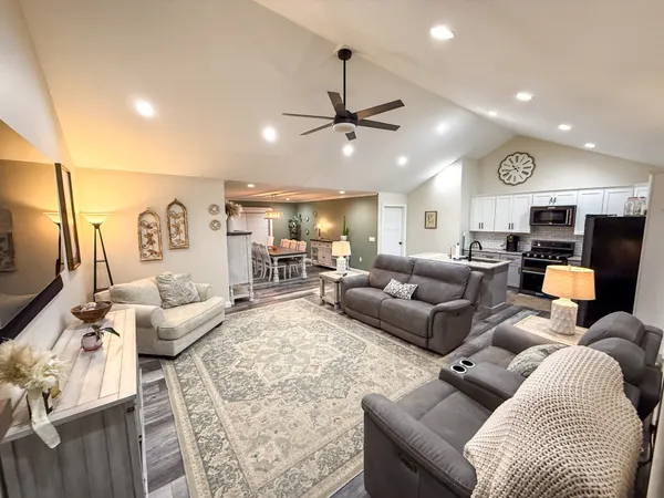 a living room with furniture kitchen view and a chandelier