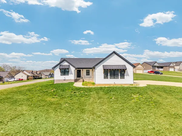 a view of a house with a big yard and large trees