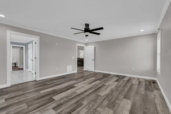 a view of empty room with wooden floor and a ceiling fan