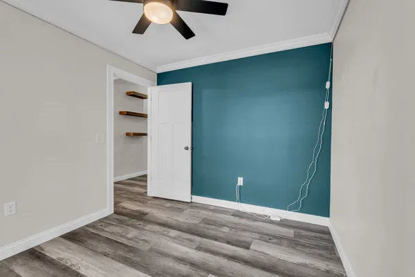 an empty room with closet and a ceiling fan
