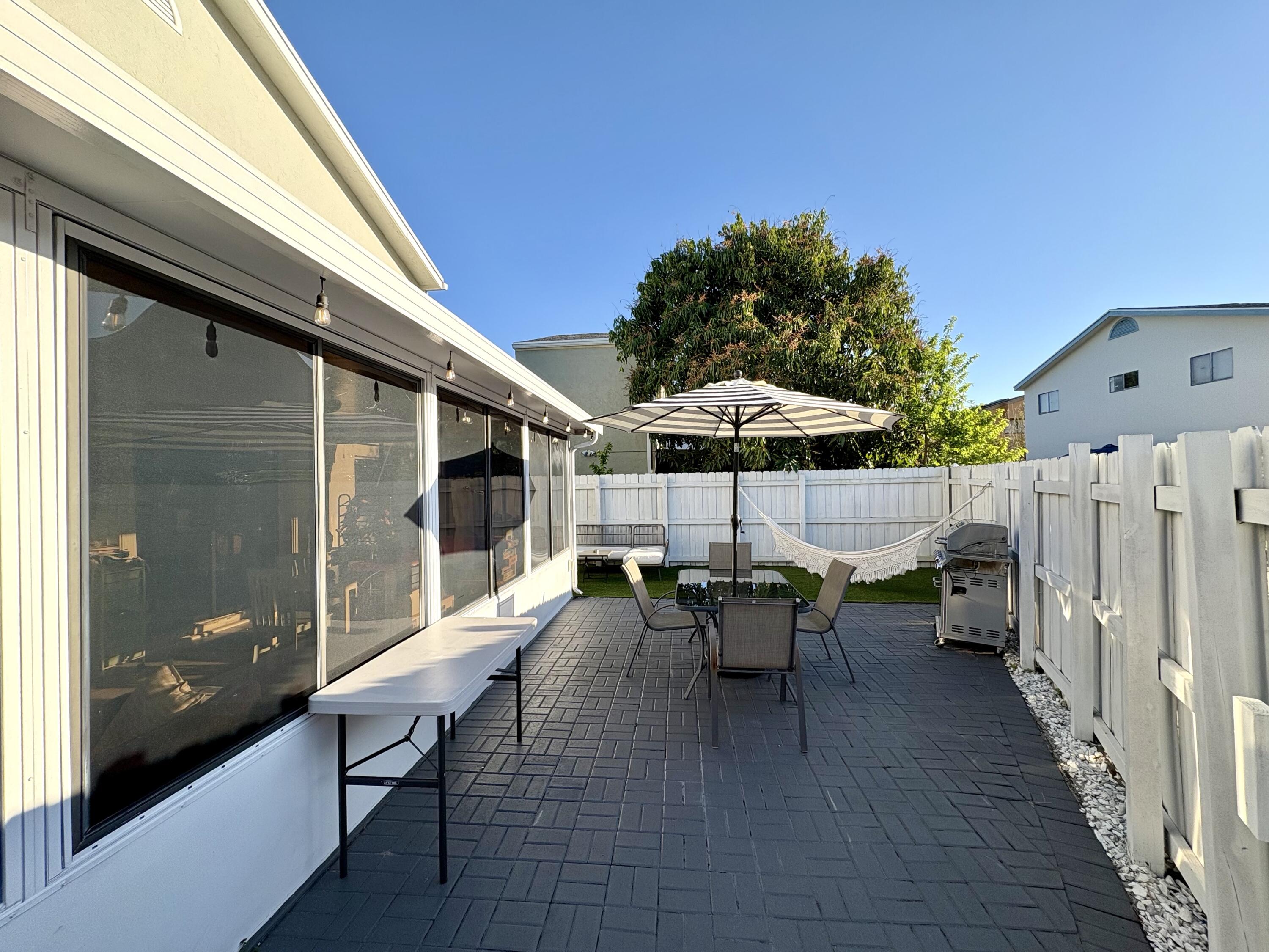 3 Kyle Way Boynton Beach, FL 33426 - Photo 31 of 36 a view of a patio with table and chairs under an umbrella with wooden floor