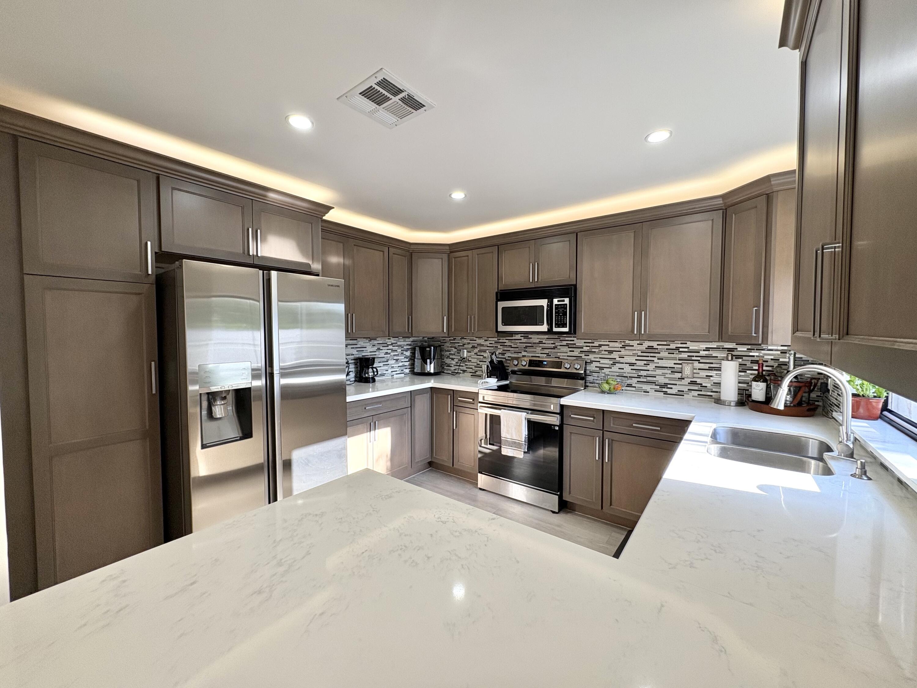 3 Kyle Way Boynton Beach, FL 33426 - Photo 10 of 36 a large kitchen with stainless steel appliances kitchen island granite countertop a refrigerator and a sink