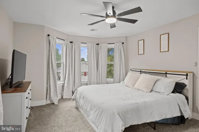 a bedroom with a large bed and a flat tv screen on dresser