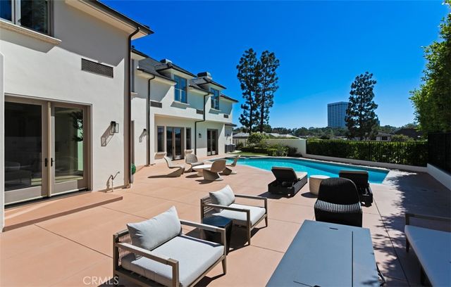 a view of a patio with couches table and chairs with plants and palm trees