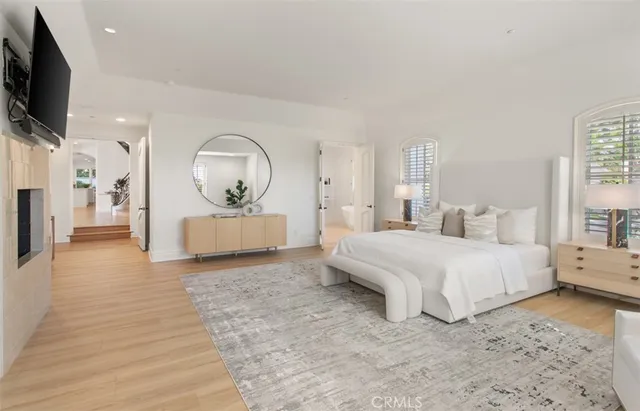 a spacious bedroom with a bed a mirror and flat screen tv