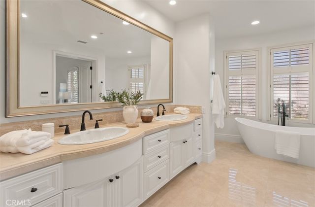 a bathroom with double vanity sinks a large mirror and a bathtub