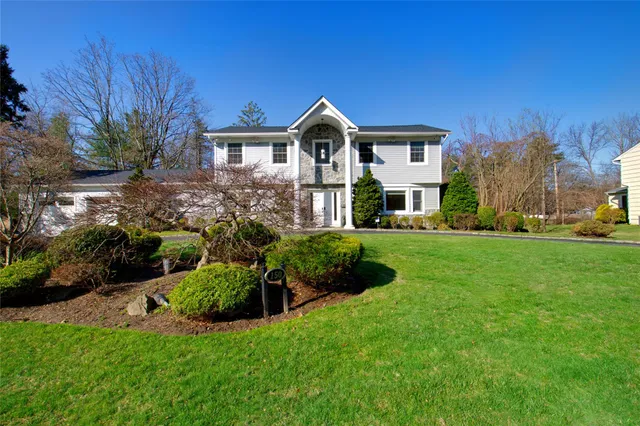 a front view of a house with a yard and trees