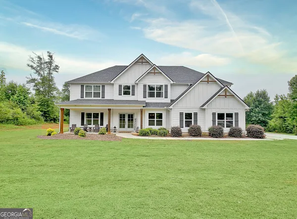 a front view of a house with a garden and trees
