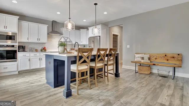 a kitchen with stainless steel appliances kitchen island granite countertop a table chairs sink and cabinets