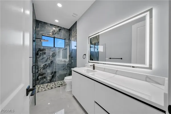 a bathroom with a granite countertop sink a mirror and a bathtub