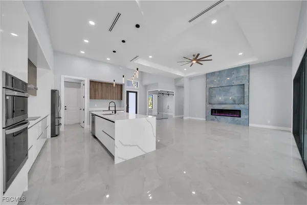 a large white kitchen with kitchen island a large counter top space stainless steel appliances and a counter top space