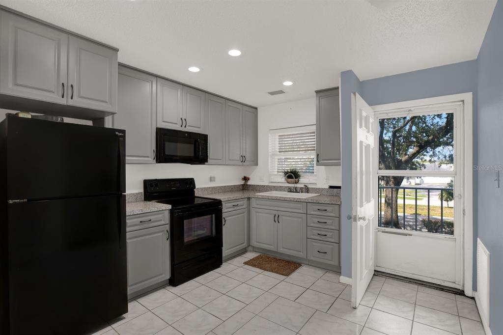 4939 Floramar Terrace, Unit 204 New Port Richey, FL 34652 - Photo 6 of 22 a kitchen with granite countertop appliances a sink and a refrigerator