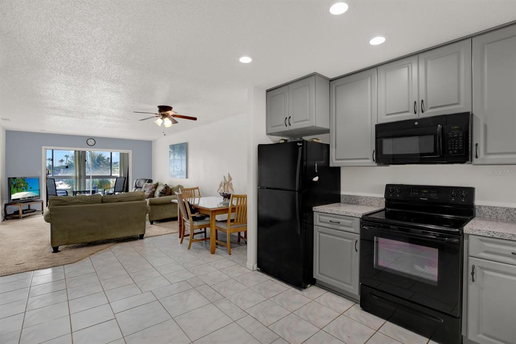 4939 Floramar Terrace, Unit 204 New Port Richey, FL 34652 - Photo 9 of 22 a kitchen with kitchen island white cabinets and stainless steel appliances