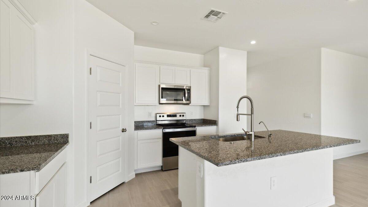2175 West Spaulding Avenue Apache Junction, AZ 85120 - Photo 6 of 7 a kitchen with granite countertop a sink a stove and cabinets