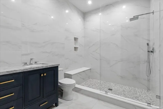 a bathroom with a granite countertop sink a toilet and shower