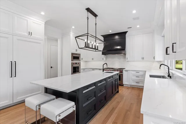 a kitchen with stainless steel appliances granite countertop a sink dishwasher a stove a refrigerator a microwave oven with white cabinets and wooden floor