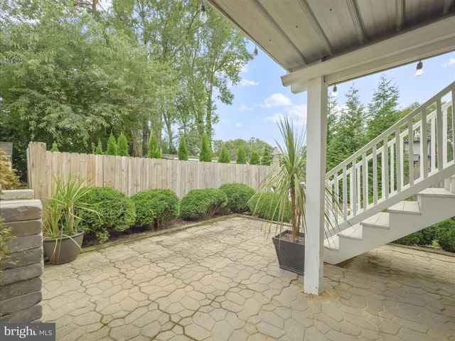 a view of backyard with seating space and trees in the background