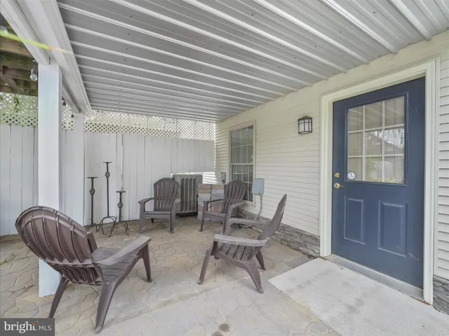 a living room with furniture a rug potted plant and a large window