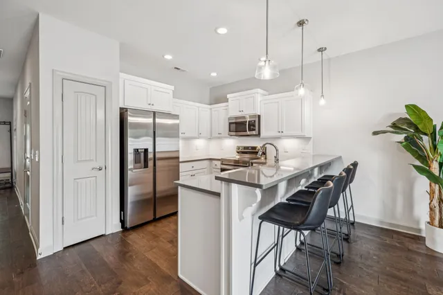 a kitchen with stainless steel appliances granite countertop a refrigerator a sink a stove a dining table and chairs