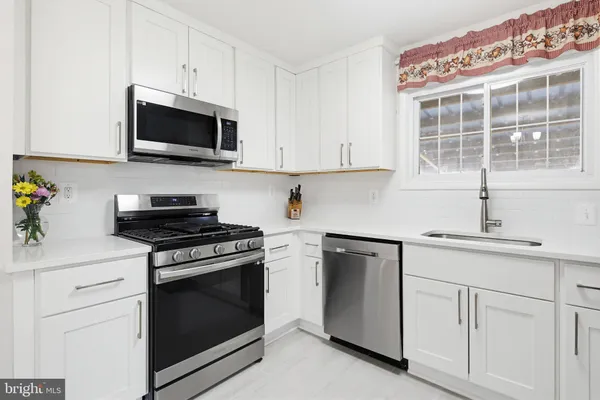 a kitchen with white cabinets and appliances