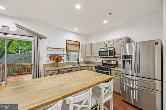 a kitchen with granite countertop a refrigerator stove top oven and sink