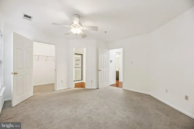 an empty room with closet and a ceiling fan