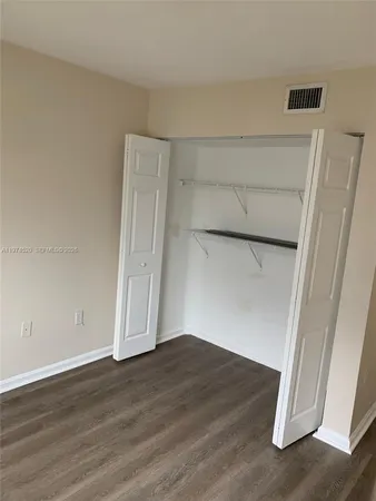 an empty room with wooden floor and cabinet