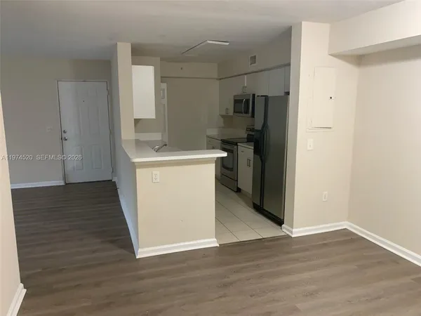 a view of a kitchen with refrigerator and wooden floor