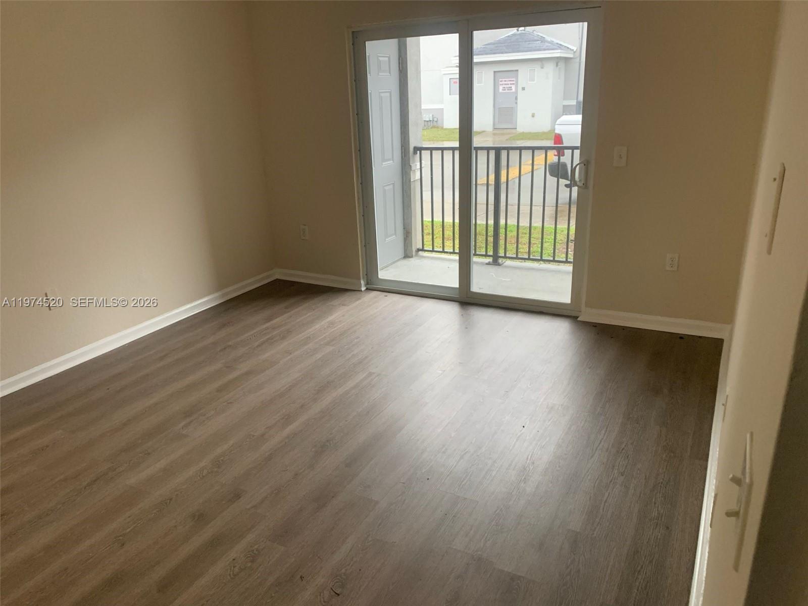 15440 Southwest 284th Street, Unit 5102 Homestead, FL 33033 - Photo 6 of 27 a view of an empty room with wooden floor and a window