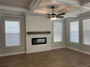 a view of an empty room with wooden floor fireplace and a window