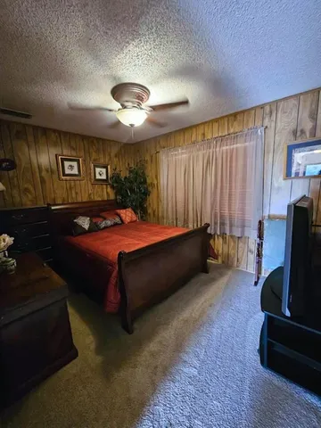 a bedroom with a bed couch and a flat tv screen