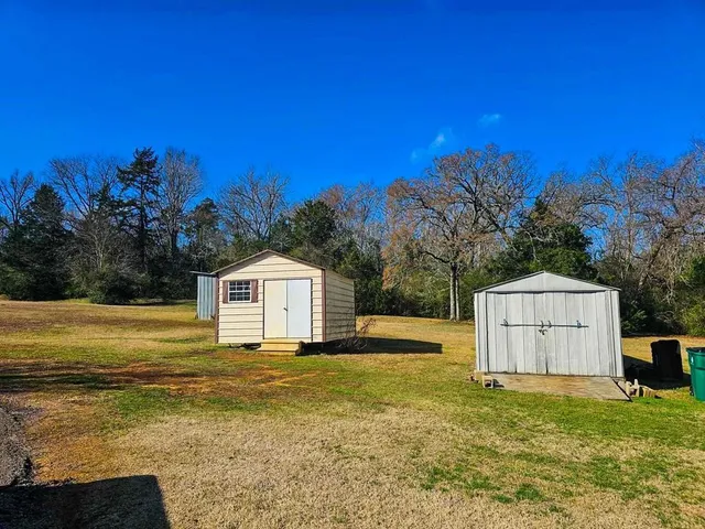 a view of a house with a yard and a large tree