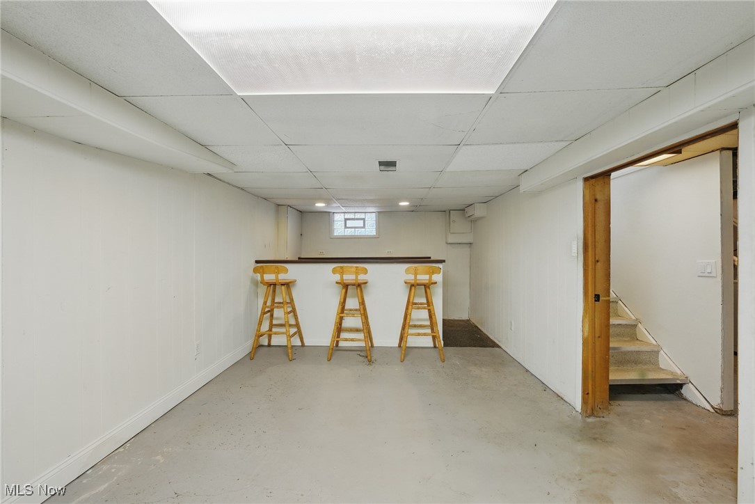 28575 White Road Wickliffe, OH 44092 - Photo 37 of 49 Below grade area with visible vents, baseboards, a bar, a paneled ceiling, and stairs