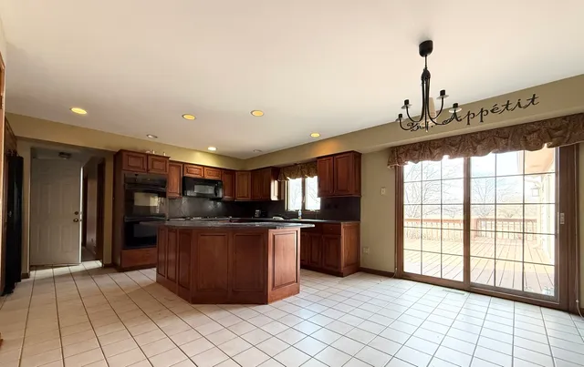 a kitchen with stainless steel appliances kitchen island granite countertop a refrigerator and a stove top oven