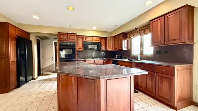 a kitchen with stainless steel appliances granite countertop a sink dishwasher and a refrigerator with wooden cabinets
